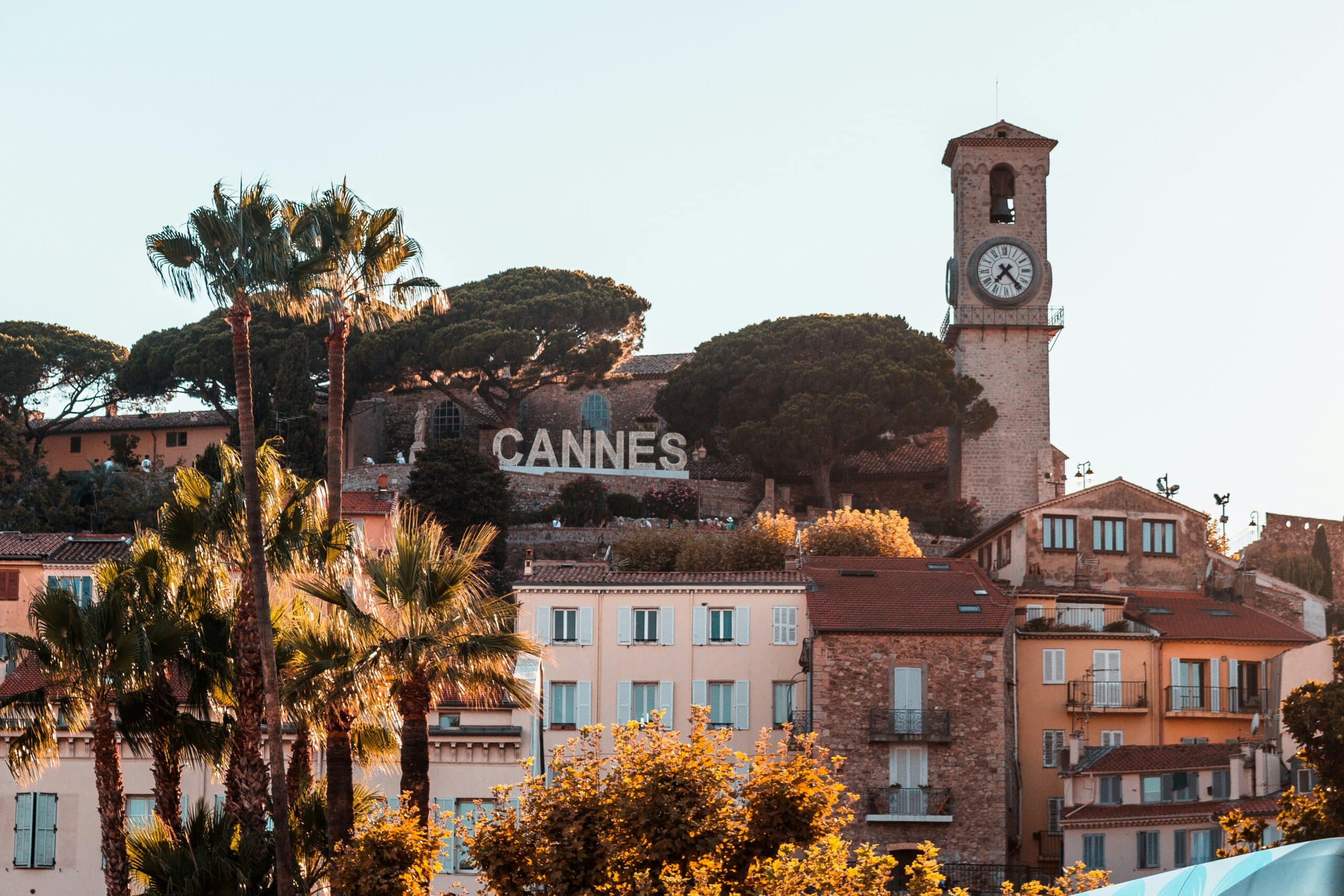 Vue panoramique de Cannes avec l'horloge et les palmiers, une destination emblématique pour des vacances de luxe.