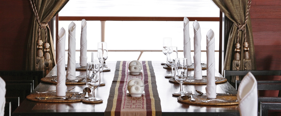 Table élégante à bord d'un luxueux bateau de croisière, offrant des expériences culinaires exclusives avec TMR Croisières.