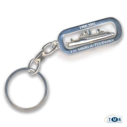 Porte-clés en métal représentant un paquebot, souvenir de croisière avec TMR Croisières.